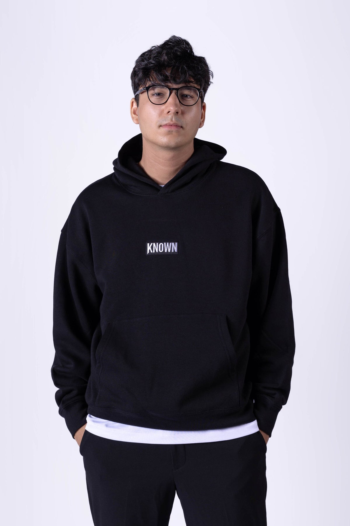 Schwarzer Hoodie von KNOWN, getragen von Model von vorn