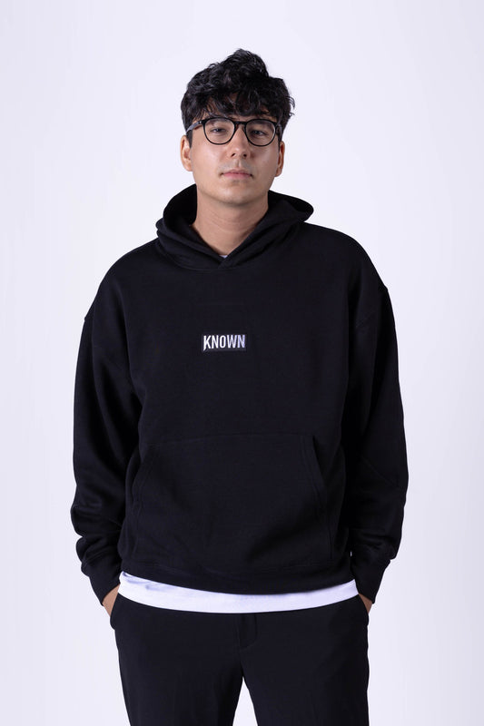 Schwarzer Hoodie von KNOWN, getragen von Model von vorn