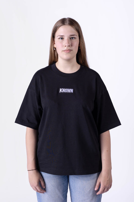 Schwarzes T-Shirt von KNOWN, getragen von weiblichem Model